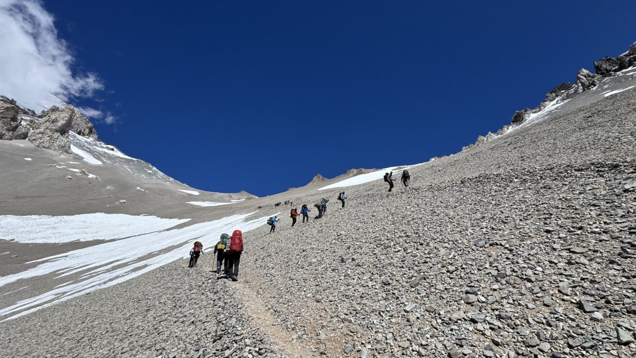 Climbers ascending steep Canaleta scree gully on Aconcagua summit day Argentina